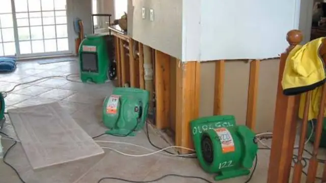 Green air movers drying a room with opened wall cavities